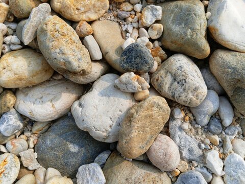 Smooth grey river gravel background texture for minimalist architectural landscape design, outdoor garden walkway paving, natural stone aggregate surface, detailed top view pattern of water eroded rou