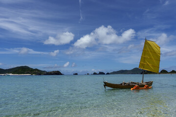 Traditional sabani sailing boat drifting on a calm turquoise lagoon, Zamami, Okinawa, Japan © keizo0211