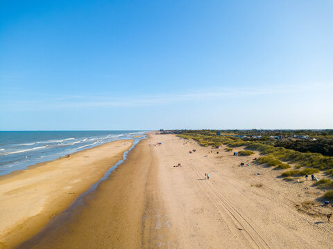 Drone shot looking along Mablethorpe beach in Lincolnshire, UK, a sandy beach beneath a blue sky