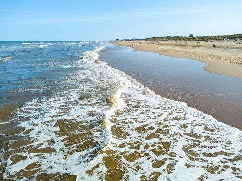 Waves breaking on the beach at Mablethorpe in Lincolnshire, UK. A sandy beach seen below a blue sky