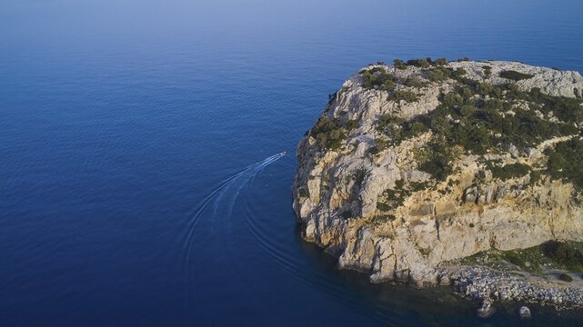 Drone shot, boat sailing along a rocky cliff over the clear blue sea, Anthony Quinn Bay, Vagies Bay, Rhodes, Dodecanese, Greek Islands, Greece