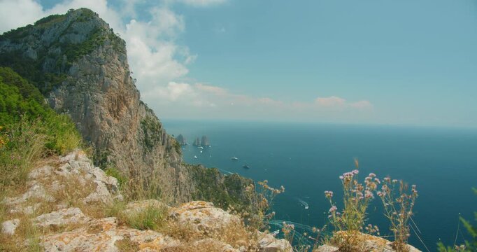 Summer view from Capri cliff overlooking Faraglioni rock and Tyrrhenian sea in Italy
