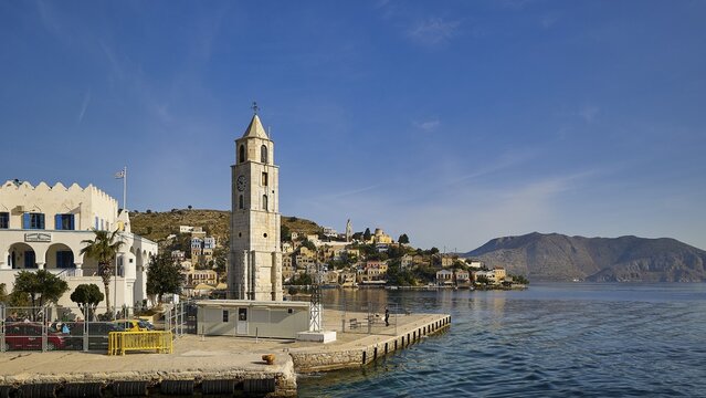 Bell tower on the coast of a Greek town, framed by sea and mountains, Symi Town, Symi, Dodecanese, Greek Islands, Greece
