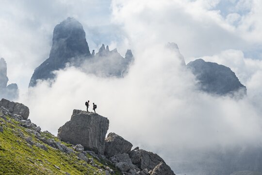 Alpine panorama, mountaineers on a large rock, fog and Torre Di Brentai and Cima Tosa, rocky mountain peaks and mountain landscape, Brenta Mountains, Parco Naturale Brenta-Adamello, Trentino, Italy
