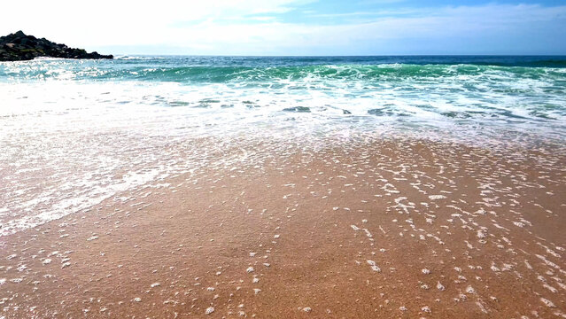 Low-angle view of sea foam receding on a sandy beach