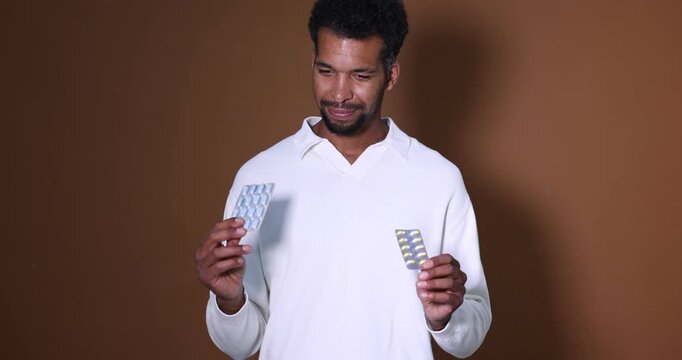 Man choosing between two blisters of pills on brown background