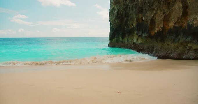 Scenic view of white sand beach and turquoise ocean waves at Nusa Penida Island Bali