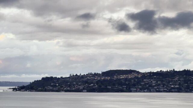 Dramatic storm clouds with pink highlights hover over North East Tacoma and Commencement Bay during sunset.