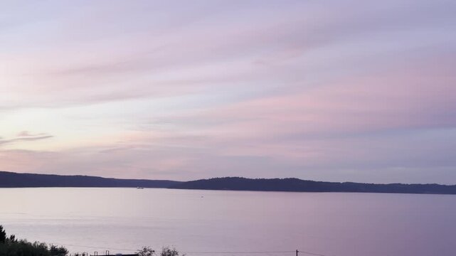 Pastel clouds streak across the sky at sunset over Commencement Bay in Tacoma Washington with Vashon Island in the distance.