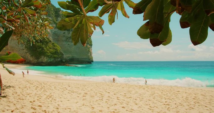 People walking on white sand beacg near turquoise ocean water on Nusa Penida Island
