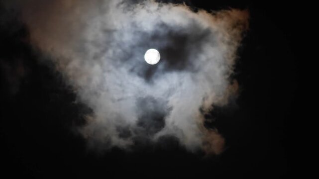 The full moon shone brightly in the dark night sky, surrounded by thin clouds that moved quickly past it until the sky slowly became brighter and clearer.