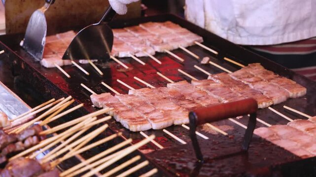 Wagyu beef skewers grilling on hot teppanyaki teppan iron plate, premium Japanese marbled meat on wooden sticks, traditional street food festival, Tokyo, Japan, market with local vendor stalls cooking