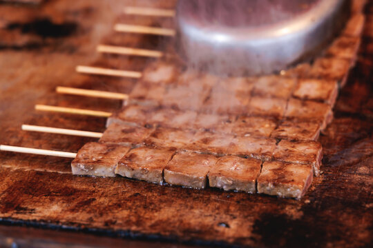 Wagyu beef skewers grilling on hot teppanyaki teppan iron plate, premium Japanese marbled meat on wooden sticks, traditional street food festival, Tokyo, Japan, market with local vendor stalls cooking