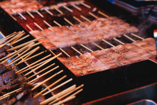Wagyu beef skewers grilling on hot teppanyaki teppan iron plate, premium Japanese marbled meat on wooden sticks, traditional street food festival, Tokyo, Japan, market with local vendor stalls cooking