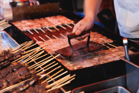 Wagyu beef skewers grilling on hot teppanyaki teppan iron plate, premium Japanese marbled meat on wooden sticks, traditional street food festival, Tokyo, Japan, market with local vendor stalls cooking