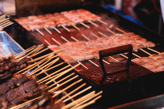 Wagyu beef skewers grilling on hot teppanyaki teppan iron plate, premium Japanese marbled meat on wooden sticks, traditional street food festival, Tokyo, Japan, market with local vendor stalls cooking