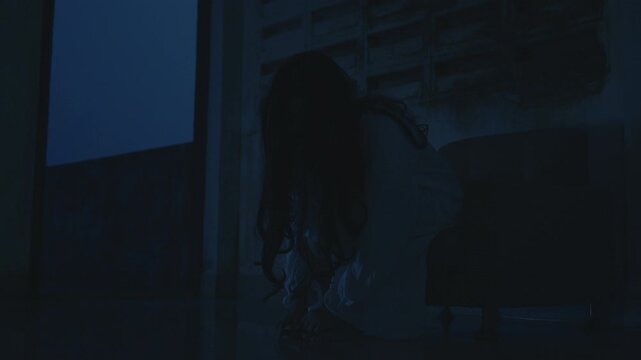 Scary halloween ghost figure appears in dark night, long black hair, wearing white costume, crouching in dark room, creating haunting eerie dead atmosphere perfect for horror concept, fear and terror.