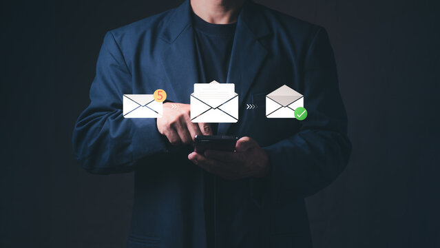 A businessman uses a smartphone with floating virtual email envelopes. Represents corporate digital communication, successful newsletter message delivery, and internet marketing campaigns.
