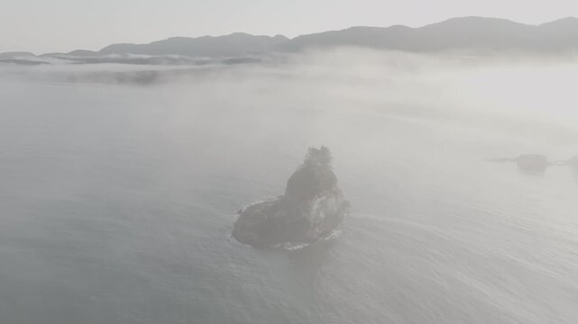 Aerial view flying through fog toward island off Washington coast , ocean waves of Olympic Peninsula (D-log / Ungraded version)