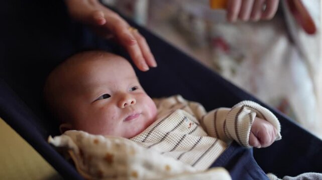 An infant looks upward as an adult hand gently touches the babys forehead The intimate close view is softly lit and nonverbal