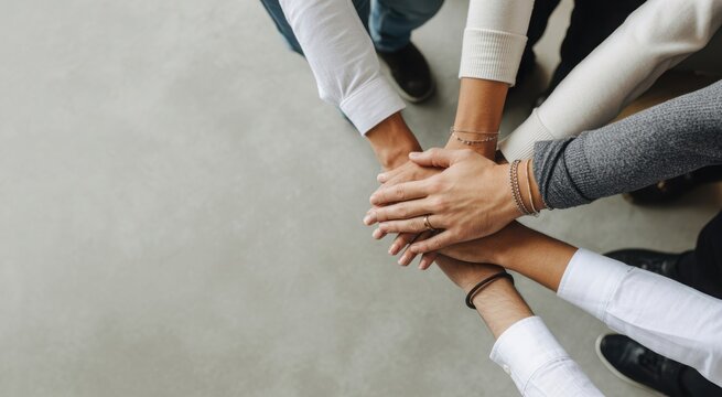Close up of diverse group of people stacking hands in unity and partnership