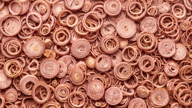 Pile of dried sliced red shallots, scattered full frame texture in pale pinkish purple