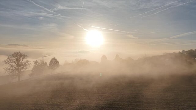 Drone footage with low level sun over the mist with small village. Shot on DJI Mavic Air 3s 4K 60fps 150mbit.
