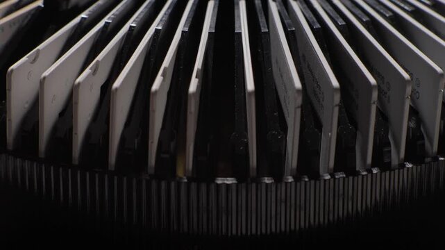 Rows of mounted photographic slides stand inside a circular vintage projector carousel, sideview as each drops down and rises back up with a flash of light