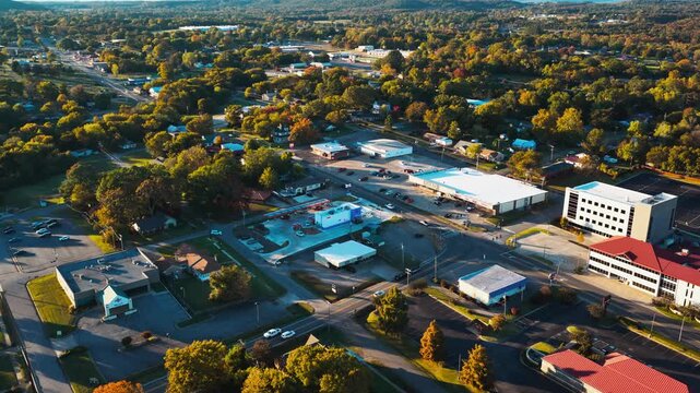 Ozark town center buildings and streets spread among autumn trees in Arkansas, aerial establishing pullback at sunset