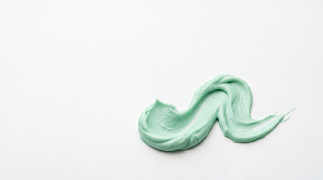 Top view macro shot of a light green cosmetic cream smear or clay mask stroke on an isolated white background with copy space, perfect for organic mint, avocado, or cica skincare marketing.