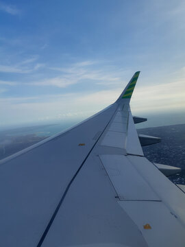 Aerial view from a passenger plane window during a flight over a tropical island and deep blue sea