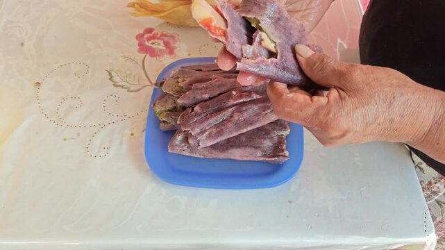 Unwrapping Hot Red Tamale Filled with Vegetables Wrapped in Corn Husk