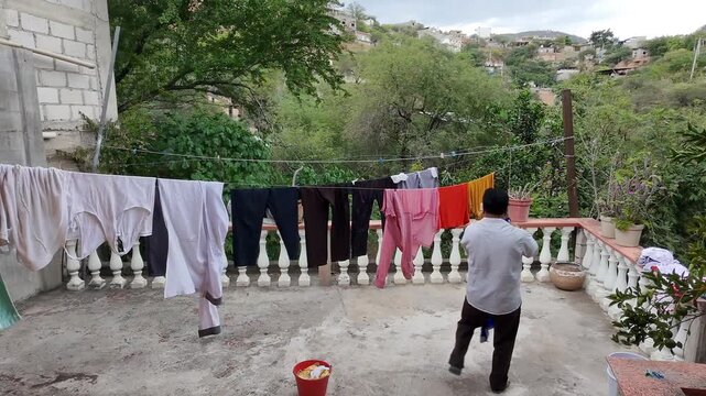 Young Man Hanging Clean Shirts on Outdoor Clothesline on Rooftop