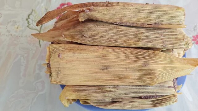 Close Up Plate of Red Tamales Wrapped in Green Corn Husk Leaves