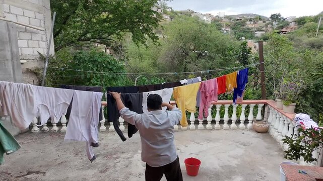 Taking Wet Pants Out of Laundry Bucket and Hanging on Clothesline