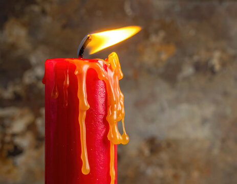 Red candle flame melted wax warm glow rustic background create quiet festive mood beside burning red candle with dripping amber wax and textured stone