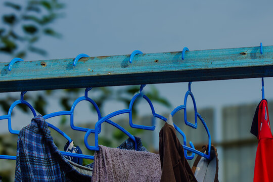 Blue plastic clothes hangers with wet laundry drying outdoor