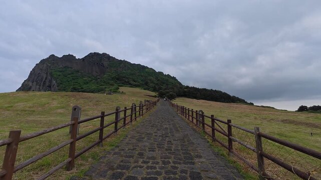 Wooden boardwalk path leading to Seongsan Ilchulbong, Jeju Island, South Korea.