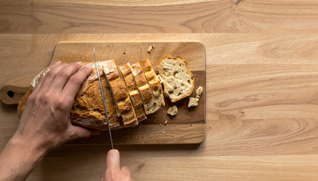 Hands Slicing a Whole Loaf of Bread on a Wooden Board to Reduce Food Waste
パンを切り分けて最後まで使い切る食品ロス削減のイメージ