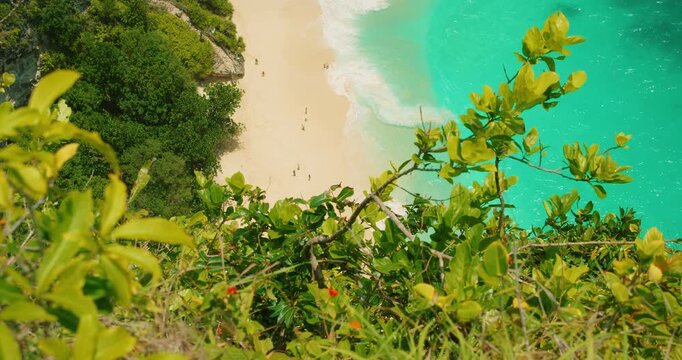 Tropical beach with turquoise water and people seen from the top cliff at Kelingking Nusa Penida Bali