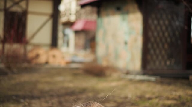 Tense outdoor confrontation with man aiming handgun toward viewer as woman turns away; muted daylight, rusted industrial setting, windblown hair and scarf, and strong sense of danger, motion, and
