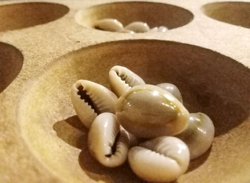 Macro shot of cowrie shells inside a wooden hole of traditional Asian Congklak board game