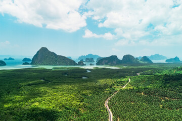 Obraz premium Panoramic aerial view of road through jungle forest Thailand at mouth of bay with high cliffs in the distance