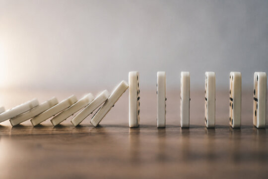 A chain of falling dominoes interrupted, focusing on the break point.