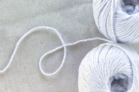 Macro of white yarn balls on a natural cotton fabric