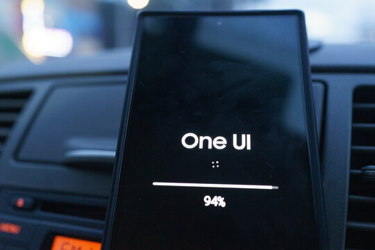 Penang, Malaysia - 30 July 2026: A close-up view of a smartphone screen displaying the Samsung One UI system update installation progress bar at 94 percent, set against a vehicle dashboard background.