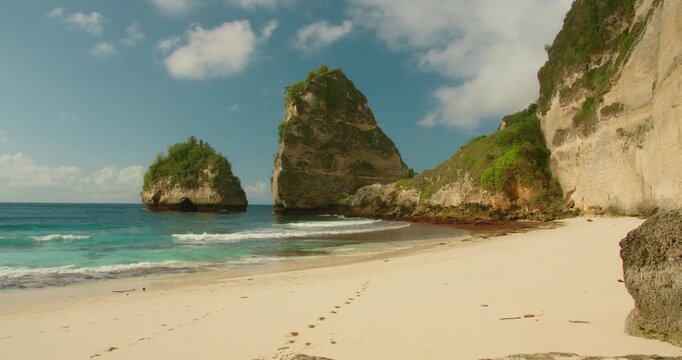 Cliffs and sea stacks tower over sandy shore at Diamond Beach Nusa Penida Bali