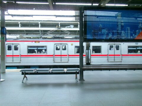 Commuter train platform with digital billboard displaying skyline art