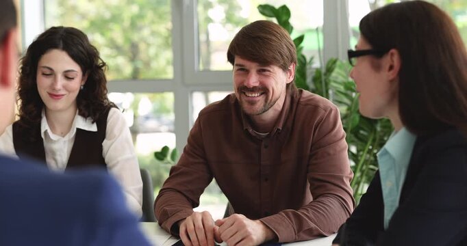 Male executive proposing successful decision to smiling diverse partners or colleagues at negotiation table in office receiving support approval during conversation in positive workplace environment