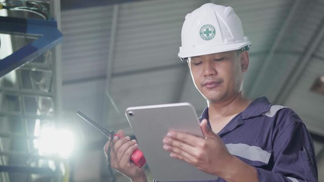 Electrical engineer is communicating with team and use radio while working on digital tablet control electrical panel in industrial plant. System PLC industrial manufacturing. Factory industry 